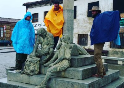 Hikers in rain gear standing around a statue